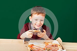 Children eat Italian pizza in the cafe. School boy is eating pizza for lunch. Child unhealthy meal concept. Hungry kids. Pizza re