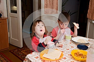 Children eating lunch at home, healthy food concept, kids enjoying bread and yogurt, sibling emotionally faces