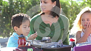 Children Eating Packed Lunch Outdoors With Teacher