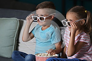 Children eating popcorn while watching TV in evening