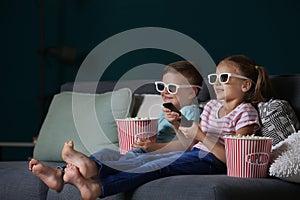 Children eating popcorn while watching TV in evening