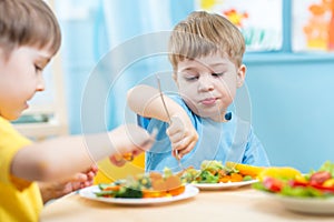 Children eating vegetables in kindergarten or at home