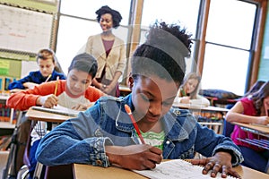 Children, education and school with a student black girl writing in a book while sitting in class for learning. Study