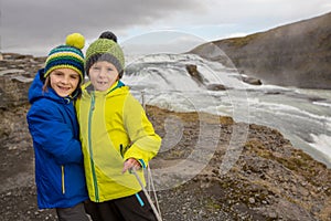 Children, enjoying the big majestic Gullfoss waterfall in mountains in Iceland
