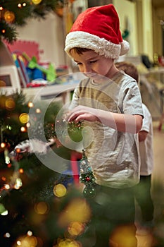 A little boy decorating a Christmas tree with his mother at home. Together, New Year, family, celebration
