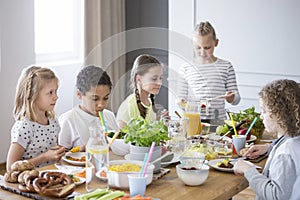 Children enjoying a healthy meal by a table in a dining room during a lunch break in a private primary school