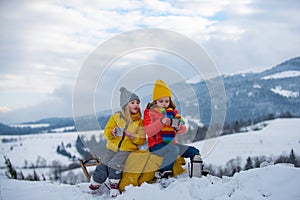 Children enjoying winter, playing with sleigh ride in the winter forest. Kids play with snow. Winter vacation concept.