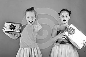 Children with excited faces pose with presents on green background.