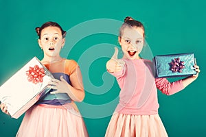 Children with excited faces pose with presents on green background.