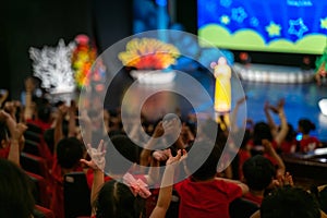 Children excitingly raise hands watching the performance in the theater