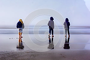 Children Explore Foggy Beach on Wet Sand