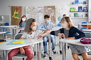 Children with face mask back at school after covid-19 quarantine and lockdown, greeting.