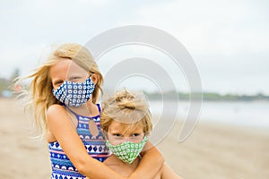 Children in face masks have fun on sea beach