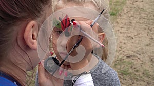 Children face painting. Artist painting little girl like ladybird. Gimbal motion