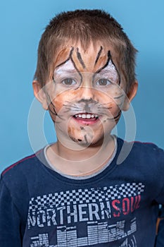 Children face painting. Boy painted as tiger or ferocious lion by make up artist. Preparing for theatrical performance. Boy actor