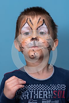 Children face painting. Boy painted as tiger or ferocious lion by make up artist. Preparing for theatrical performance. Boy actor