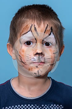 Children face painting. Boy painted as tiger or ferocious lion by make up artist. Preparing for theatrical performance. Boy actor