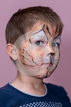 Children face painting. Boy painted as tiger or ferocious lion by make up artist. Preparing for theatrical performance. Boy actor