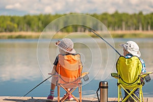 Children with fishing rods sit on a wooden pier and fish