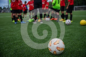 Children during a football match listen to the coach`s directives, close-up on the football ball