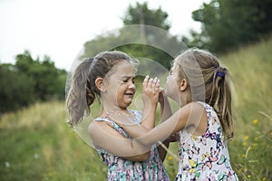 Children friend girls playing whispering on flowers grass in vac