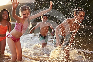 Children With Friends Enjoying Evening Swim In Countryside Lake