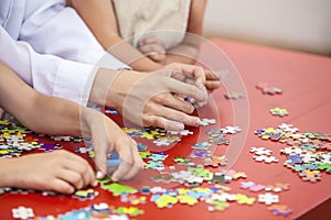 Children, friends hands assemble the puzzle on the table color