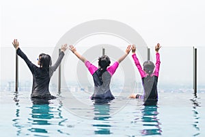 Children friendship concept with happy girl kid group having fun playing together in swimming pool on rooftop hotel