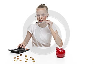 Children Frugal Concepts. Blond Teenage Girl Posing With Coins and Moneybox. Calculating Income With Calculator For Savings