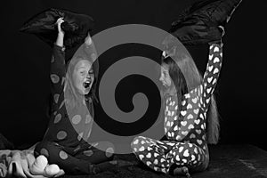 Children and fun time concept. PJs party for children: girls shouting and fighting with pillows