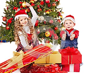 Children with gift box near Christmas tree.