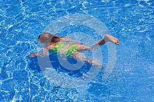Children gilr swimming underwater in blue pool