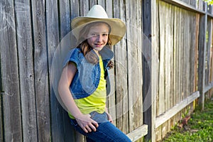 Children girl as kid cowgirl posing on wooden fence