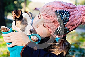 Children girl kissing her puppy terrier doggy on the park