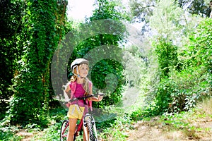 Children girl riding bicycle in forest smiling