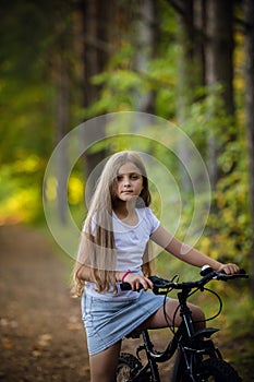 Children girl riding bicycle outdoor in forest smiling.