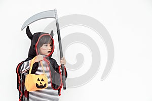 Children girl wearing mysterious Halloween dress holding a scary pumpkin and sickle