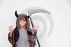 Children girl wearing mysterious Halloween dress holding a sickle on white background