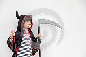 Children girl wearing mysterious Halloween dress holding a sickle on white background