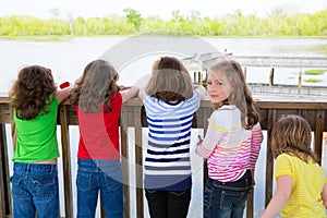 Children girls back looking at lake on railing
