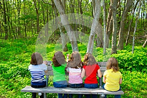 Children girls sitting on park bench looking at forest