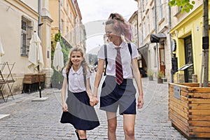 Children going to school, two girls sisters walking together, holding hands