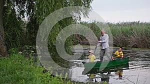 children with grandfather on the boat waving hello, grandmother greets the family from fishing on background of