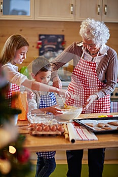 Children and grandmother preparing Xmas cookies