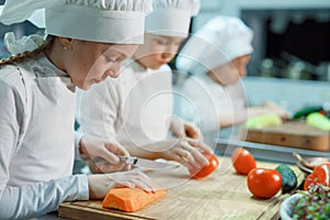 Children grind vegetables in the kitchen of a restaurant.