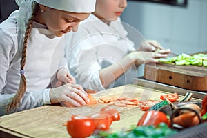 Children grind vegetables in the kitchen of a restaurant.