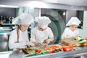 Children grind vegetables in the kitchen of a restaurant.