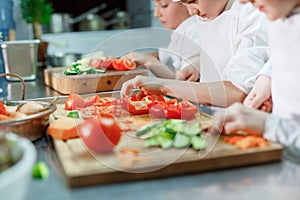 Children grind vegetables in the kitchen of a restaurant.