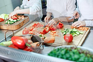 Children grind vegetables in the kitchen of a restaurant.