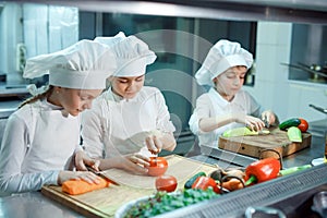 Children grind vegetables in the kitchen of a restaurant.